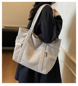 Close-up of beige corduroy tote bag showing front zipper pockets and ribbed texture