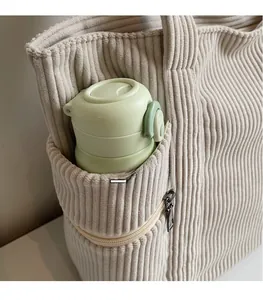 Detailed view of beige corduroy tote bag showing practical side pocket for water bottle