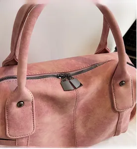 Detail view of smooth double zippers and matte pink leather texture on tote bag