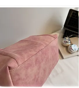 Detailed view of pink suede tote bag material with smooth texture on a desk