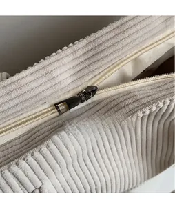 Detailed macro view of the metal zipper pull and ribbed corduroy texture on this tote bag