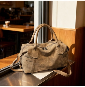 Detail shot of vintage brown Boston bag with distressed leather texture on a cafe bar
