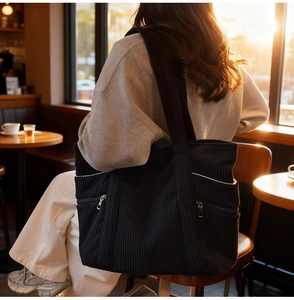Detail of black corduroy tote bag showing contrasting white trim and zipper pocket