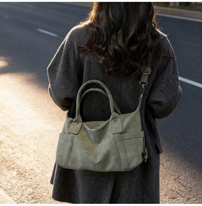 Outdoor shot of olive green vintage tote bag with functional side pockets and shoulder strap