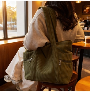Detail of dark green corduroy tote bag featuring side metal zippers and large capacity