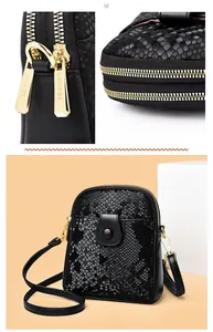 Close-up of golden dual zippers and snake pattern leather on a black crossbody bag