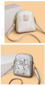 Detail of snake pattern leather crossbody phone bags in cream and silver with thin straps