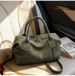 Detail of dark green suede tote bag with double zippers and strap on leather car seat
