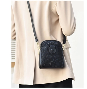 Detail of black crocodile texture crossbody bag featuring gold hardware and multiple pockets