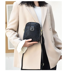 Close-up of black crossbody bag with faux snake texture and elegant gold buckle detail