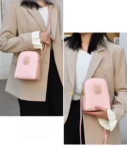 Detail of pink textured leather mini crossbody bag with zipper and flap pocket