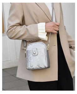 Silver snakeskin crossbody bag with metal snap pocket shown on a beige suit outfit