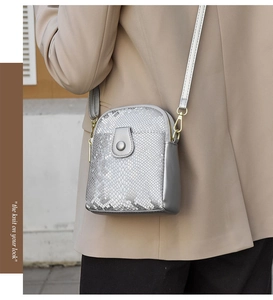 Detailed view of silver snakeskin texture crossbody bag on a beige blazer model