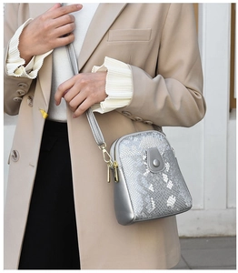 Detail of silver snake pattern crossbody bag with gold zippers worn with beige blazer