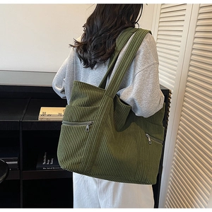Detail of large olive green corduroy tote bag featuring ribbed texture and zip pocket