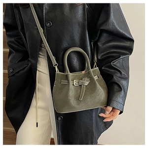 Detailed view of olive green retro bucket bag featuring white contrast stitching and buckle