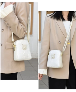Detail of white snakeskin embossed crossbody bag with gold hardware and magnetic flap