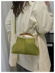 Retro green suede shell bag with wooden handle shown from a side view on a model