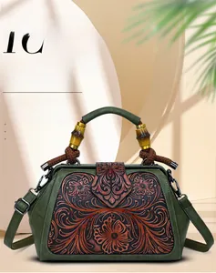 Macro detail of dark green leather handbag featuring brown floral embossing and bamboo handle