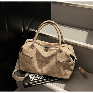Macro view of khaki Boston bag showing pebbled leather texture and reinforced stitching