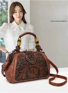 Detailed relief flower carving on a vintage brown leather bag with bamboo handle