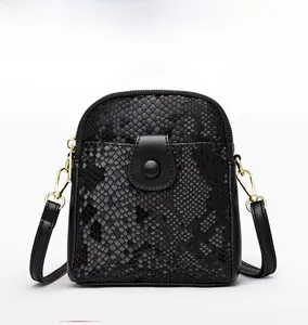 Detailed view of black crocodile-textured mini crossbody bag with golden hardware