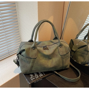 Detail view of dark green suede Boston handbag with dual handles and matte texture