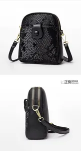 Detail of snake pattern leather texture and gold hardware on black crossbody bag