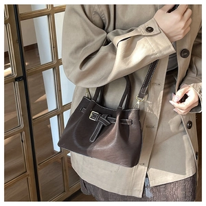 Detail of dark brown leather bucket bag with metal buckle and white stitching detail