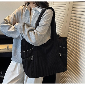 Macro detail of black corduroy tote bag featuring silver zipper and side pocket