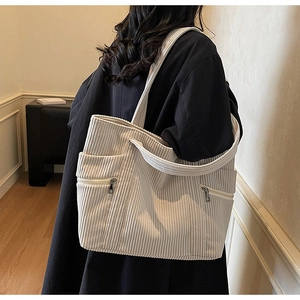 Detailed view of large off-white corduroy tote bag showing ribbed texture and side zipper