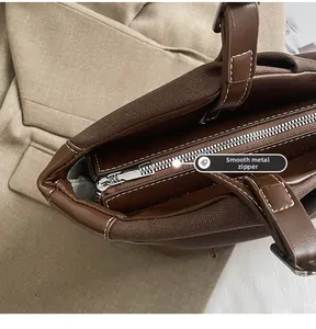 Detailed macro view of the smooth silver metal zipper on the brown canvas handbag