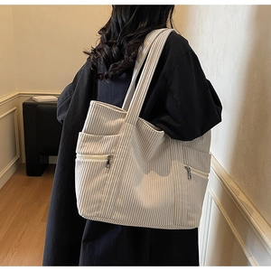 Detail of soft corduroy tote bag showing vertical ribbed texture and side zipper pocket