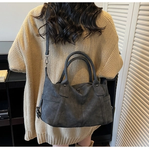 Detail view of large grey matte tote bag with shoulder strap worn over knit sweater