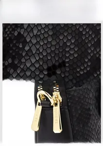 Detail of black faux snakeskin leather texture and gold dual zippers with engraved logo