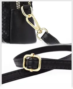 Detail of detachable gold metal hooks and adjustable snake-embossed leather strap on black bag
