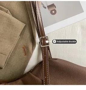 Detail of adjustable metal pin buckle on brown canvas shoulder bag with leather strap