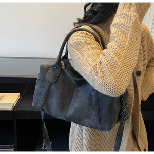 Detail view of charcoal grey Boston bag with vintage matte texture and metallic buckles
