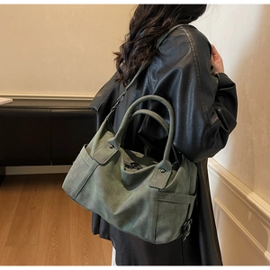 Detail of dark green vintage Boston bag showing matte texture and adjustable strap on model
