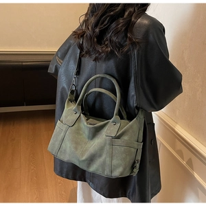 Detail of vintage green matte leather tote bag featuring a round handle and adjustable strap