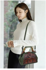 Detail of vintage emerald leather bag with floral relief and bamboo handle on a model