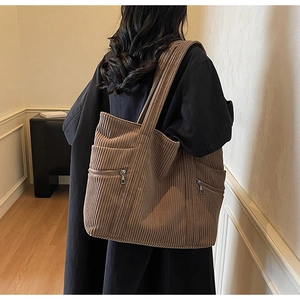 Brown corduroy tote bag shown on shoulder featuring large capacity and front dual zippers