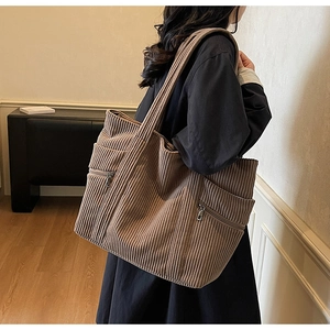 Detail of brown corduroy tote bag showing textured fabric and front silver zipper pocket