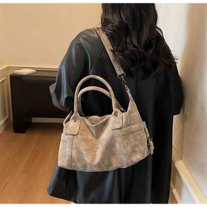 Grey vintage textured tote bag with detachable strap shown on a model in a minimal room