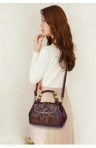 Detailed close-up of intricate hand-carved floral leather and a bamboo handle on a handbag