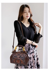 Ethnic retro handbag with wooden handle and floral embossing worn by a model