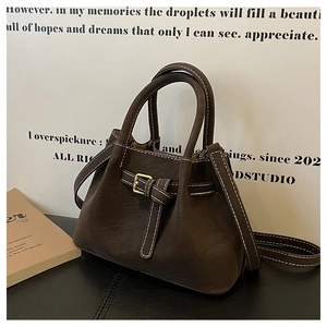 Detail of dark brown matte bucket bag showing white contrast stitching and buckle design