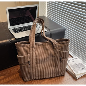 Detail of a large brown corduroy tote bag showing its ribbed texture and side zipper