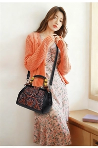 Detail of floral embossed handbag with bamboo handle shown on a fashion model