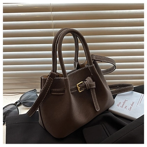 Detail of dark brown bucket bag with contrast stitching and golden buckle accents